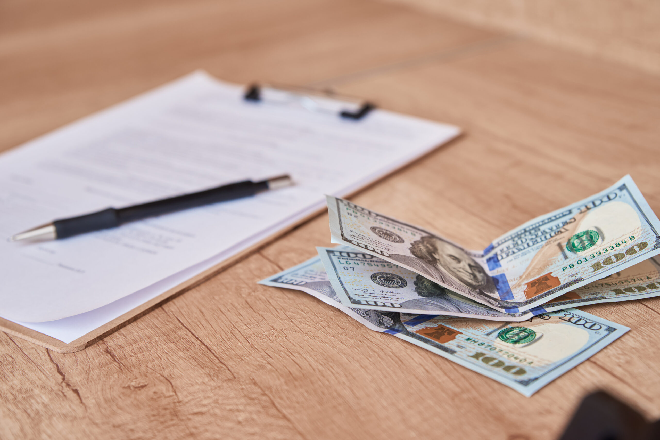 Document, pen and dollar bills on table, close up